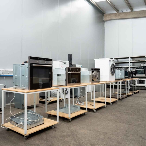 Het repair centre van elektrohersteller Dokter Elektro in Mariakerke bij Gent. Hier staan vele tientallen elektrische defecte toestellen. Witgoed, kapotte wasmachines, ovens en kookplaten op een rij. Ze wachten op een herstelling door Marc en zijn collega Luc.