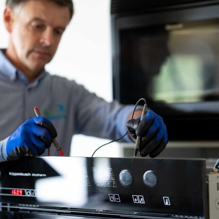 Elektrohersteller Marc Leyre aan het werk. Op de foto voert hij een herstelling uit bij een klant. De Inbouwoven is defect. Met draagstel en meetapparatuur gaat Dokter Elektro Marc Leyre na welk onderdeel het defect in de oven veroorzaakt.